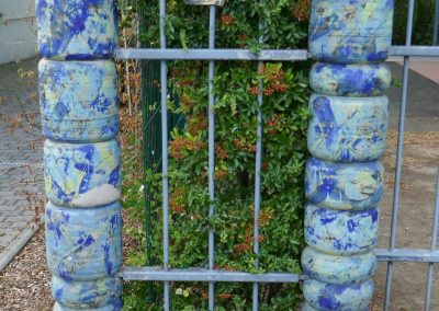 Künstlerische Einfassung einer Hecke mit blauen Keramiksteinen