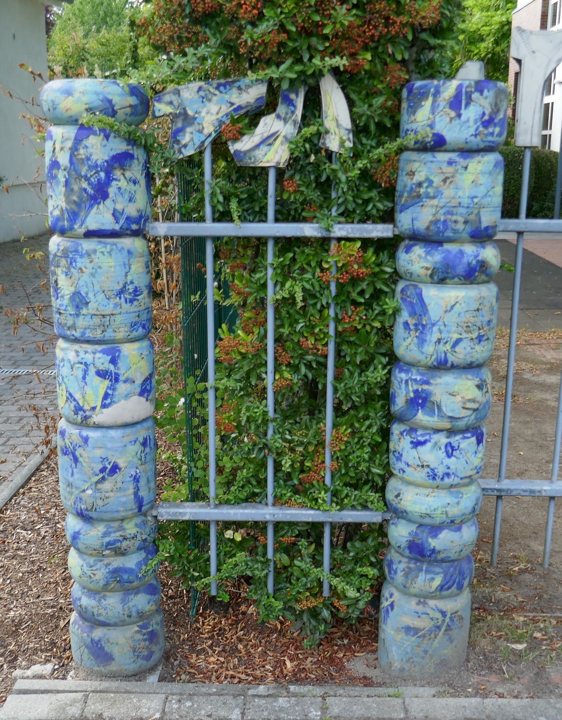 Künstlerische Einfassung einer Hecke mit blauen Keramiksteinen