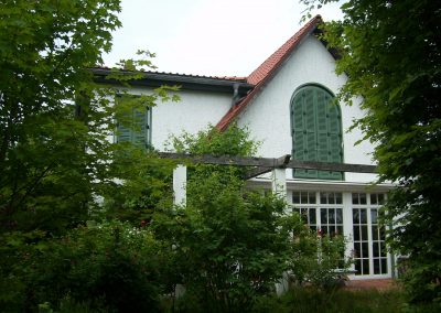 Rückansicht Gebäude mit Terasse und grünen Fensterläden