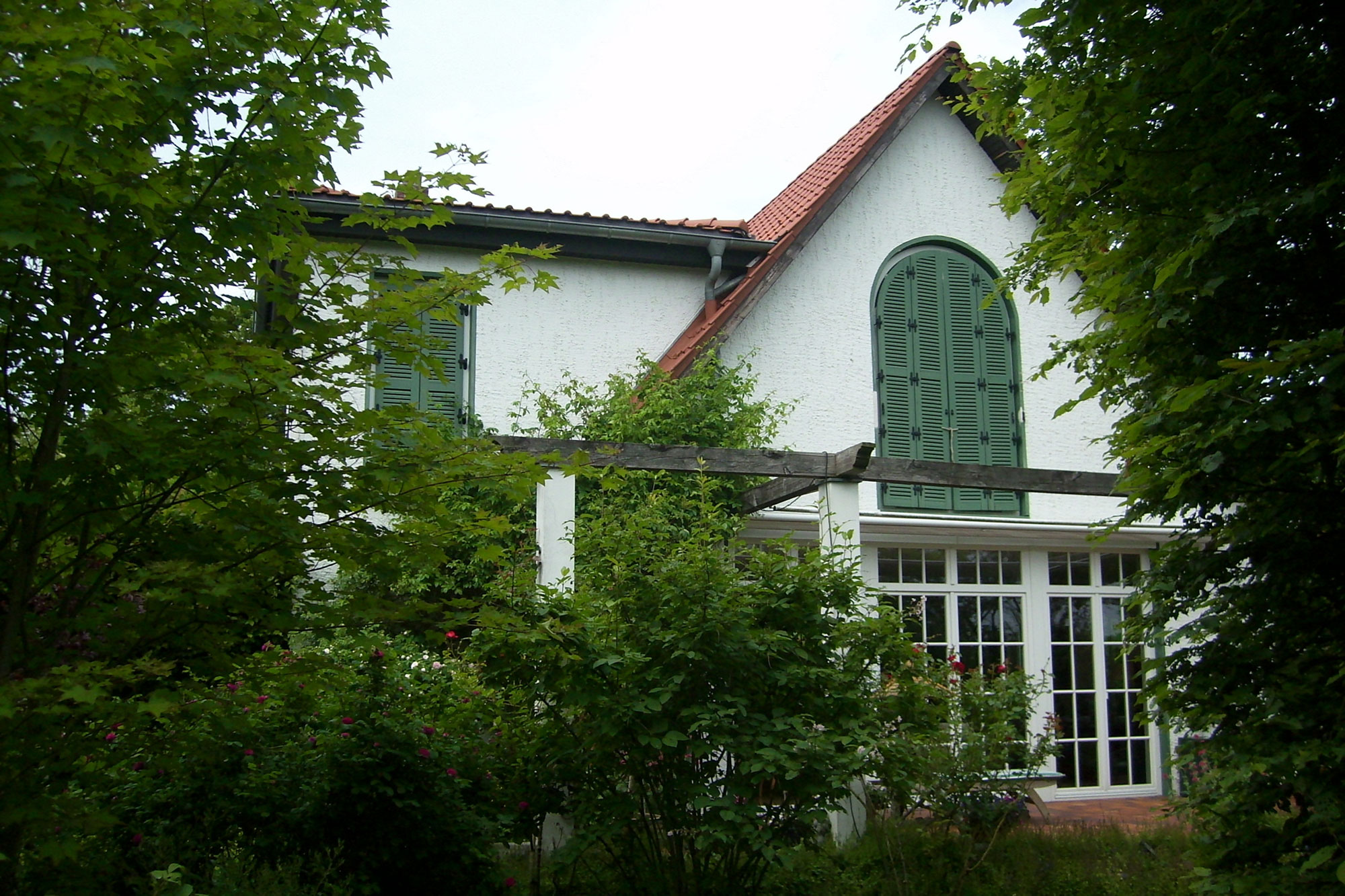 Rückansicht Gebäude mit Terasse und grünen Fensterläden